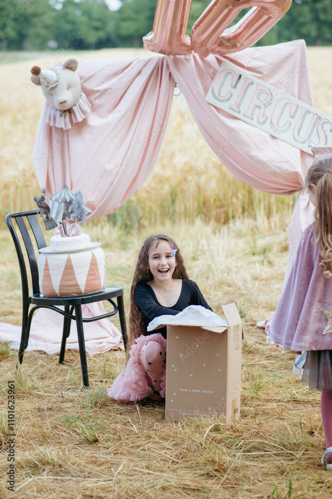 Naklejka premium little girl opens her birthday present, astonishment and happiness. Birthday party.
