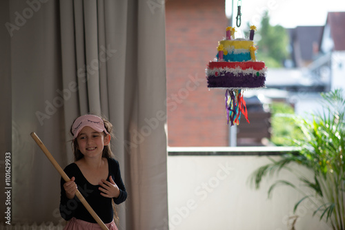 little girl breaks pi?ata on her birthday with her eyes closed photo