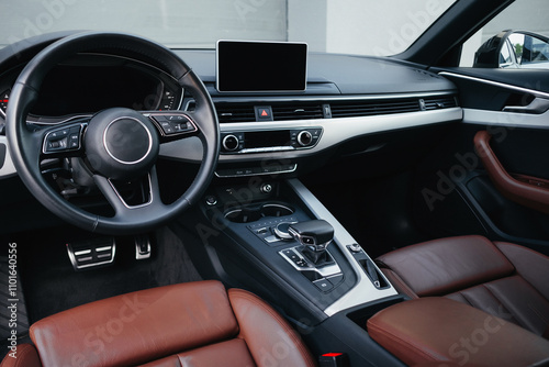 Modern brown car interior, leather steering wheel, climate control, navigation, air ducts, deflectors on the car panel, interior details.