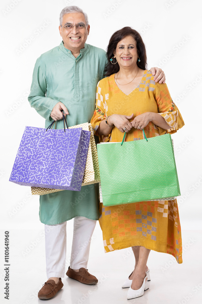 Indian senior couple looking into camera with shopping bags Indian senior couple looking into camera with shopping bags
