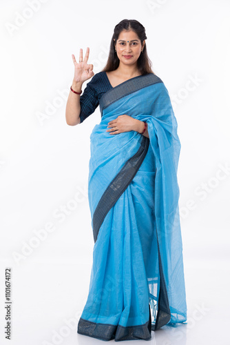 Woman making OK sign against white background.