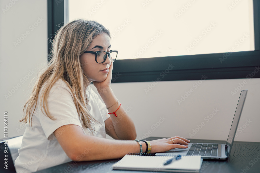 Happy young blonde business woman entrepreneur using computer looking at screen working in internet sit at office desk, smiling millennial female professional employee typing email on laptop workplace