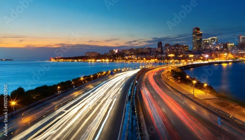 The dynamic motion blur of a bustling urban highway during the evening rush hour, showcasing streaking headlights and taillights beneath a stunning city skyline illuminated against the