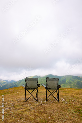 Camping chairs and misty mountains. Camping concept vertical photo