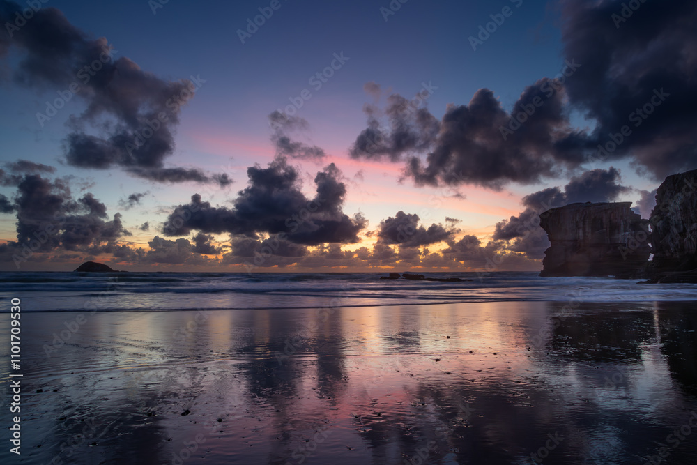 Fototapeta premium Stunning Muriwai Beach covered with clouds at sunset