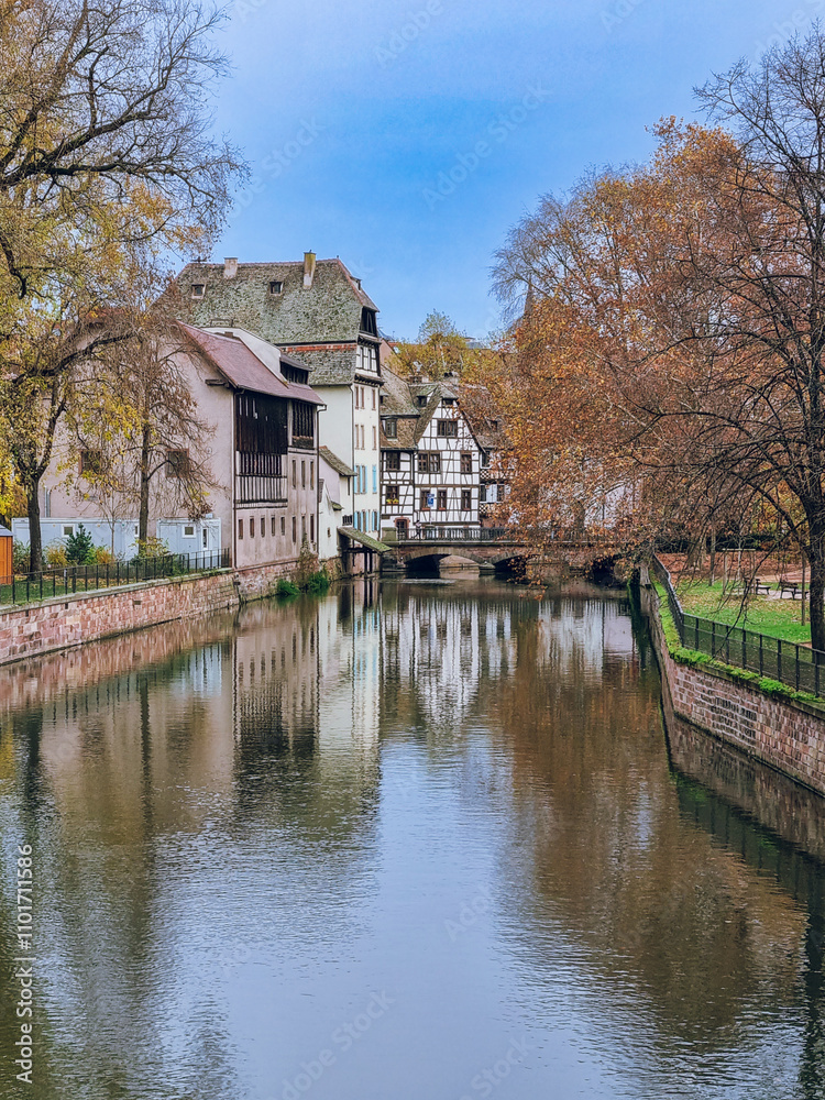 Fototapeta premium Picturesque river view in La Petite France in Strasbourg with half-timbered houses and water reflection, Colourful architecture, canal and blue sky in November, Travel destination, Alsace, France