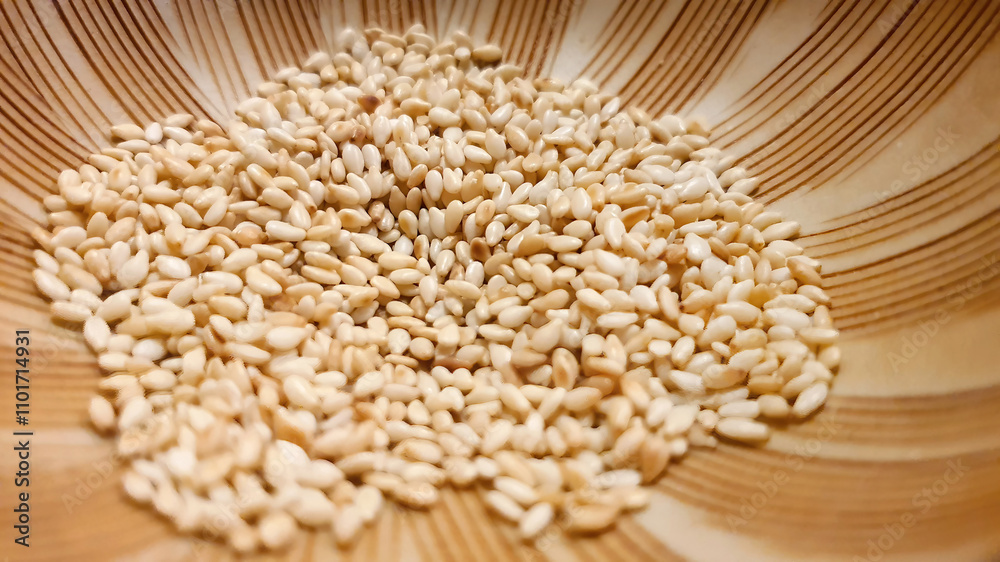 Close up shot of Roasted white sesame seeds in Japanese mortar grinding bowl ready to serve, Japanese menu, aromatic nuts and seeds, coating ingredient flavor Close up shot of Roasted white sesame seeds in Japanese mortar grinding bowl ready to serve, Japanese menu, aromatic nuts and seeds, coating ingredient flavor