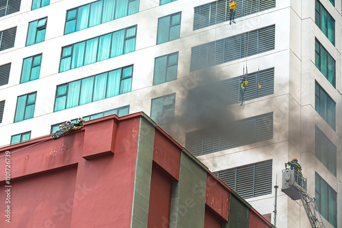 Exercises for evacuating the wounded during a fire using a rope descent method. A person descends on a rope from the windows of a high-rise building. Smoke in residential building