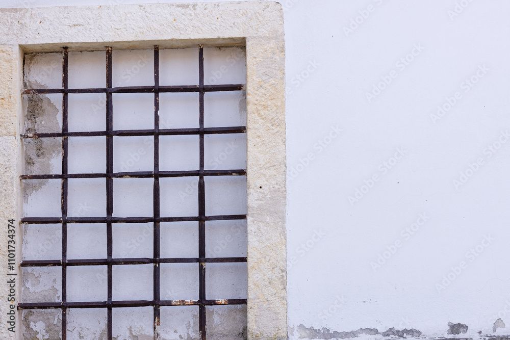 Fototapeta premium Opening in the wall in the old house is covered with a metal grate and plastered stone