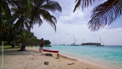 Man kayaks in San Blas Island in Panama, with his dog