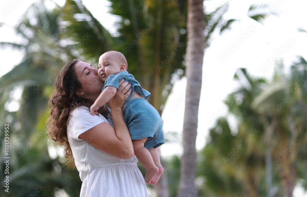 Naklejka premium Mother and her baby son playing on the beach during summer vacation