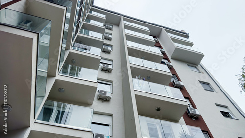 Photo of Low-Angle View of a Modern Apartment Building with Glass Balconies and Air Conditioners