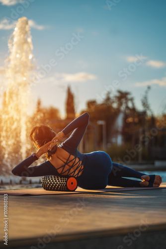 active fitness woman practicing muscular relaxation exercise with massaging foam roller, person stretching with fascial release equipment after sports training, back pain and body stiffness release photo