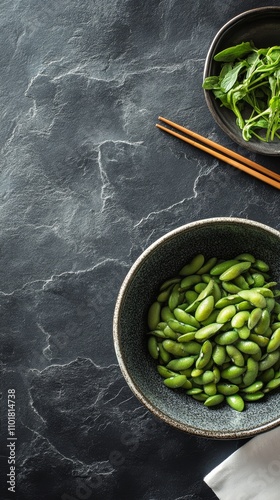Fresh edamame in bowl with chopsticks on dark surface ready for a nutritious ...
