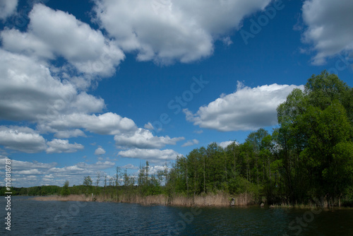 The lake during the summer in sunny warm weather with soft white clouds.