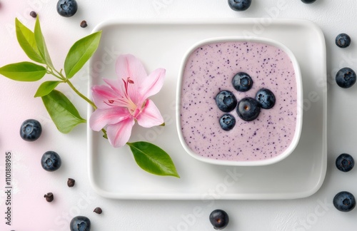 Creamy blueberry yogurt in a bowl surrounded by fresh berries and flowers