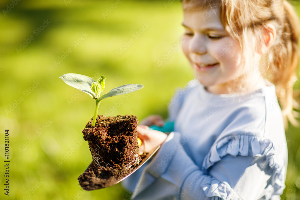 Φωτογραφία Close-up of little toddler girl holding garden shovel with green plants seedling in hands