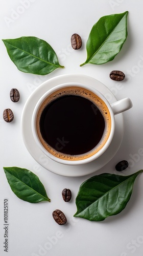 Freshly brewed coffee with coffee beans and green leaves arranged around a wh...