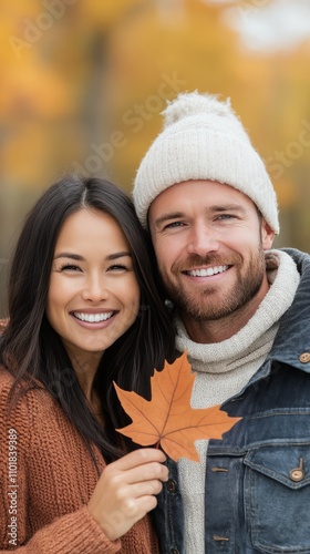 Young couple smiling together in autumn setting with colorful leaves and warm...
