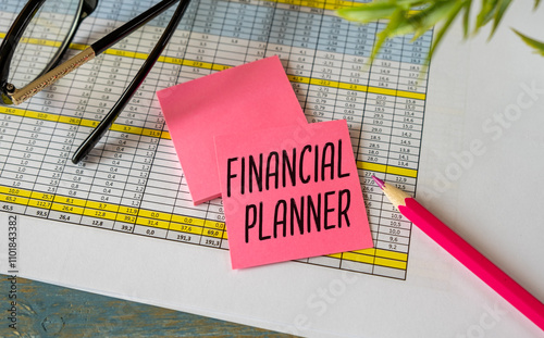 Financial Planner text on notepad on chart with keyboard and calculator on a grey background