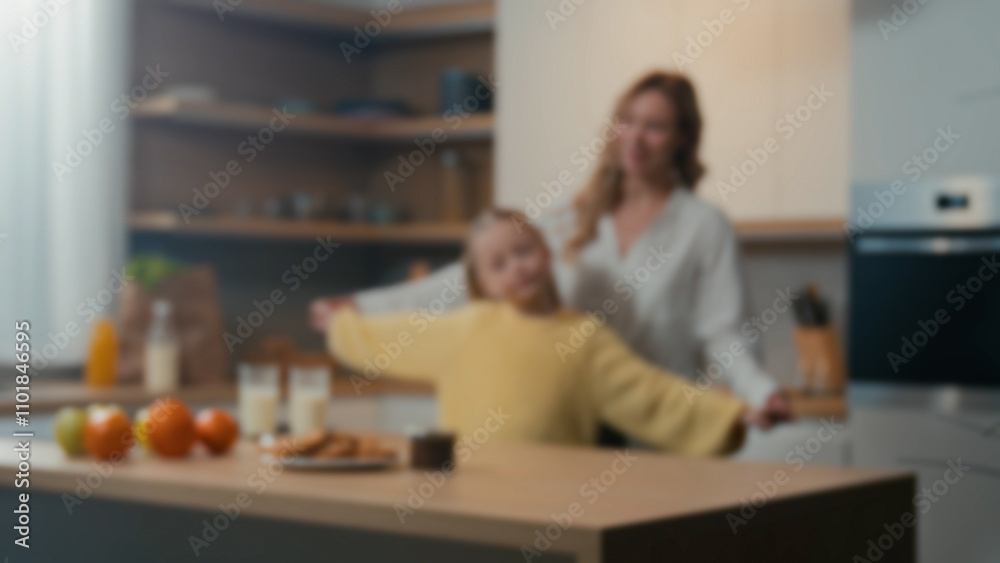 Blurred defocused view family mom and little daughter enjoy funny dance in kitchen together. Mother woman babysitter having fun with adolescent child kid girl holding hands dancing to music at home Blurred defocused view family mom and little daughter enjoy funny dance in kitchen together. Mother woman babysitter having fun with adolescent child kid girl holding hands dancing to music at home