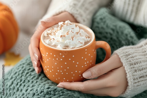 Cozy hands holding a warm cup of pumpkin spice latte topped with whipped cream