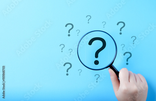 Question Mark and Root Cause Analysis Concept. A hand holding a magnifying glass over a large question mark surrounded by smaller ones on a blue background, symbolizing analysis and problem-solving.