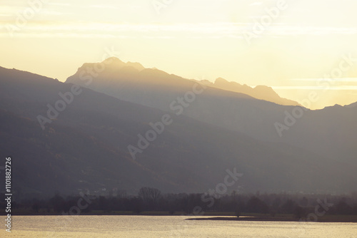 Sunset on the lake in Plav: view towards the mountains of Prokletije National Park, illuminated by the golden rays of the setting sun. Autumn evening in the east of Montenegro. Travel in the Balkans. photo