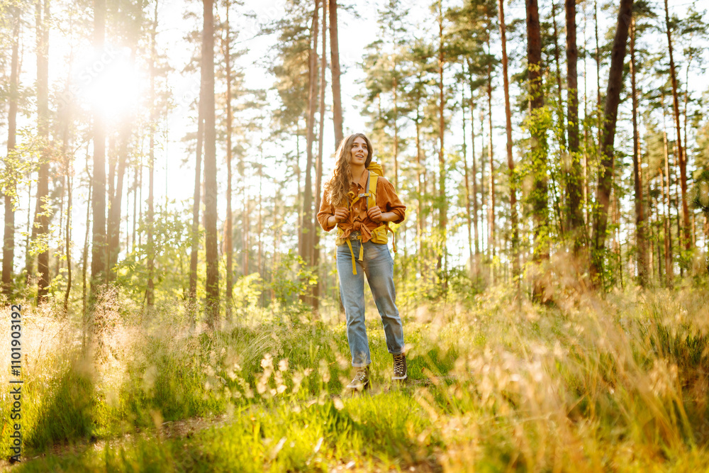 Female backpacker tourist looking up on trees and enjoying nature scenery. Active lifestyle. Hiking. Female backpacker tourist looking up on trees and enjoying nature scenery. Active lifestyle. Hiking.