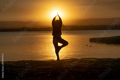 silueta de una mujer haciendo equilibrio en un paisaje hermoso al atardecer