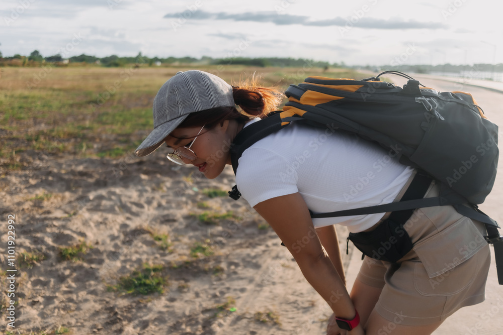 Asian Thai woman traveller carry backpack, resting hands won knees after long walking, traveling alone at countryside in Thailand. Asian Thai woman traveller carry backpack, resting hands won knees after long walking, traveling alone at countryside in Thailand.