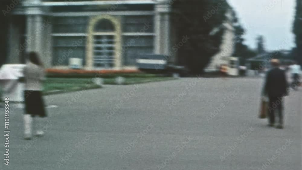 Retro film, People walk along wide pedestrian city street with green trees, flower beds. Pedestrians travel by urban Soviet street. Town lifestyle. Calm, measured city life. Vintage 1980s archive