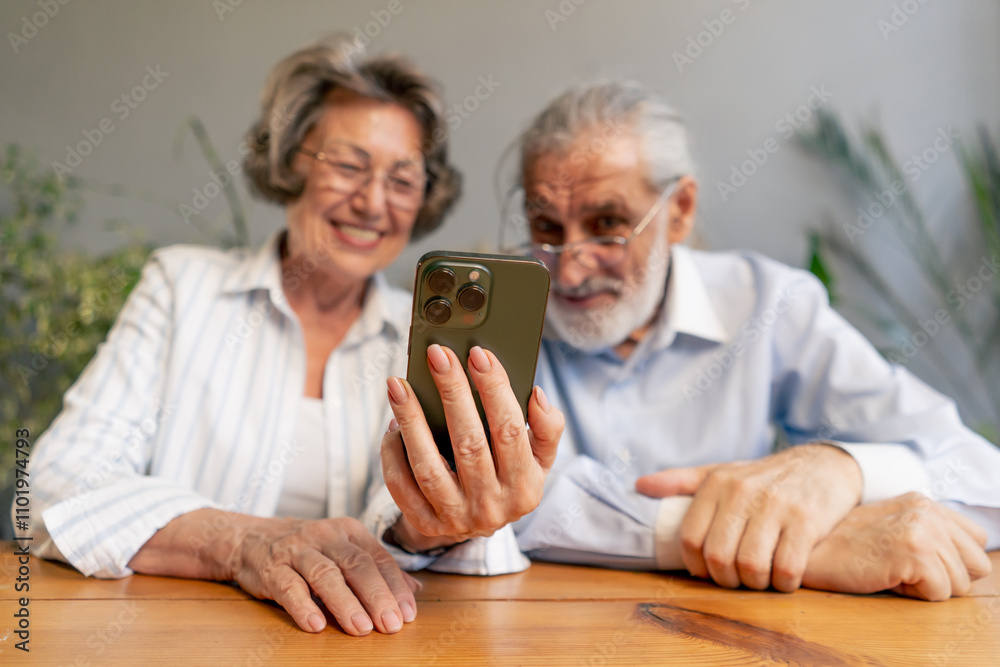 elderly people sitting at a table together watching social networks on the phone funny videos happy old age elderly couple pleasant memories leisure time in old age warm feelings support in old age