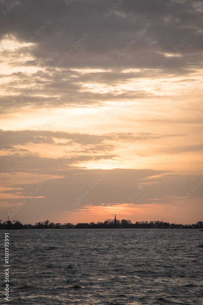 Sunset at Langweerder Wielen (Frisian: Langwarder Wielen), Frisian Lake in the Netherlands. View of the church tower of Langweer. Sunset at Langweerder Wielen (Frisian: Langwarder Wielen), Frisian Lake in the Netherlands. View of the church tower of Langweer.