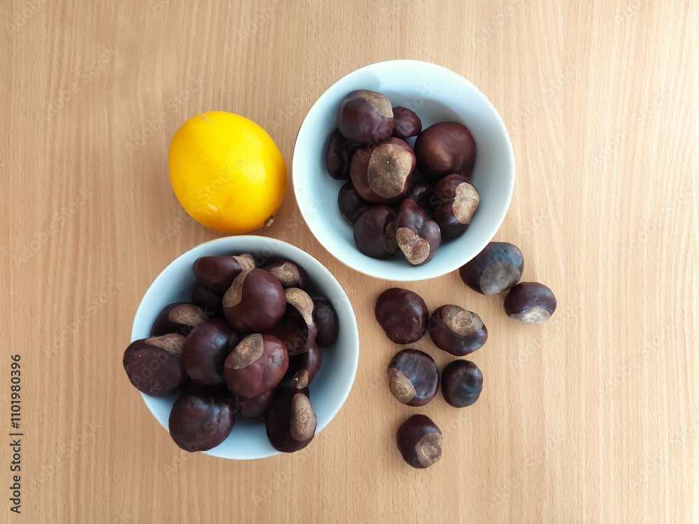Fototapeta premium Yellow lemons and shiny brown chestnuts on the table