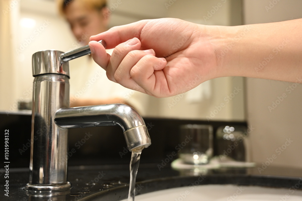 A close-up of a hand turning on a faucet with water flowing, cleanliness, hydration, and the importance of daily hygiene routines A close-up of a hand turning on a faucet with water flowing, cleanliness, hydration, and the importance of daily hygiene routines