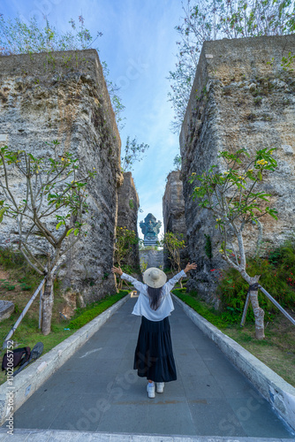 The Garuda Wisnu Kencana (GWK) statue a monumental landmark, standing 121 meters tall in the Garuda Wisnu Kencana Cultural Park, Bali, looks majestic from the gap in the rock cliff. photo