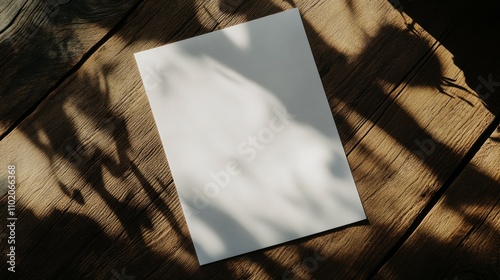 A4 paper on dark brown table, casting sharp shadows across table and paper
