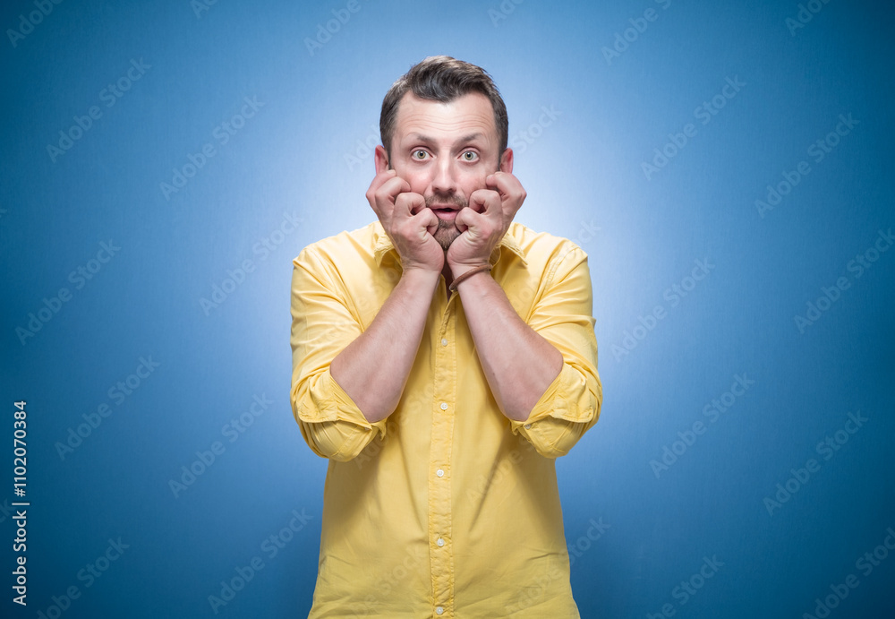 Mistake. Frightened young man stare to you over blue background, dresses in yellow shirt Mistake. Frightened young man stare to you over blue background, dresses in yellow shirt