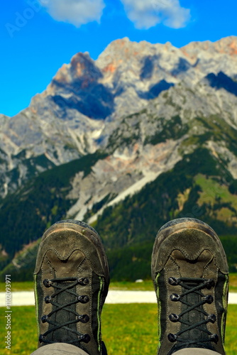 Nahaufnahme von Wanderschuhen mit Berglandschaft im Hintergrund (Fokus liegt im unteren Bildteil auf den Schuhen)