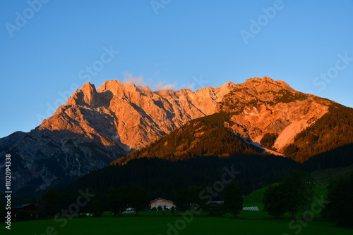 Rot leuchtende Bergkette durch Sonnenuntergang angestrahlt (Alpenglühen)