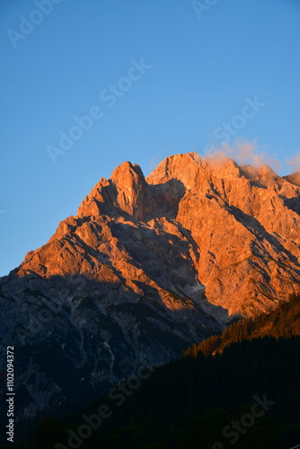 Rot glühende Bergkette im Sonnenuntergang mit blauem Himmel im Hintergrund (Alpenglühen)
