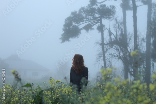 mulher caminhando em meio a plantação em dia de neblina photo