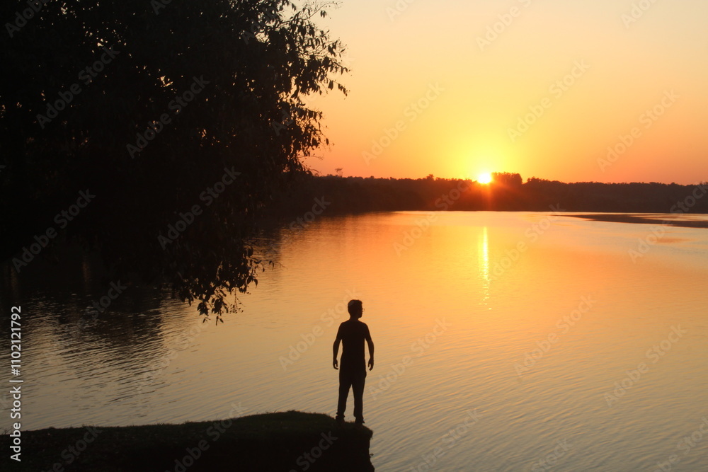 silhueta de homem em por do sol na beira do rio iguaçu em capanema, paraná silhueta de homem em por do sol na beira do rio iguaçu em capanema, paraná