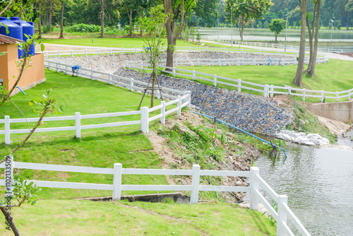 White fence with green grass hill and mountain,blue sky,Lush green golf Course,rest and relax in park near city,big tree in garden,Green grass field,Nature landscape,space for text. photo