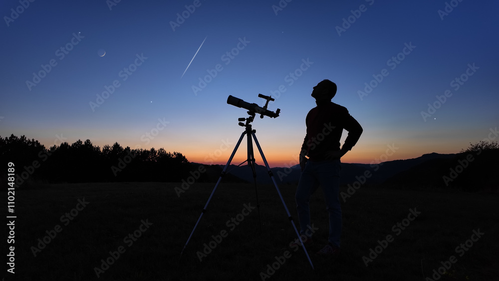 Amateur astronomer looking at the evening skies, observing planets, stars, Moon and other celestial objects with a telescope.