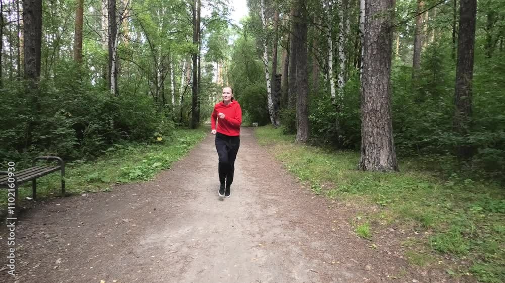 Woman training running on forest path in summer, front view Woman training running on forest path in summer, front view