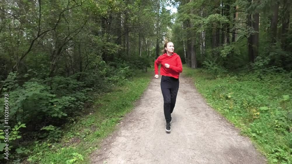 Woman running along forest alley in summer, front view Woman running along forest alley in summer, front view