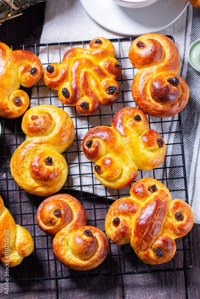 Traditional saffron Swedish buns lussekatt in different shapes, served with cocoa on a wooden table. Buns for St. Lucia's Day.