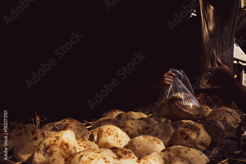 a person handing a bag of bread to a buyer 